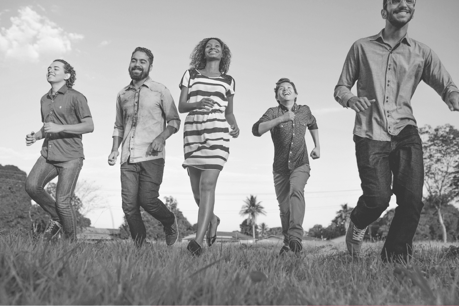 Photo of five people running in a field towards the camera